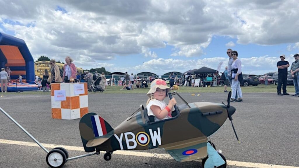 A small boy taking a ride of toy plane. Blackbushe Air Day 2024 Camberley, UK